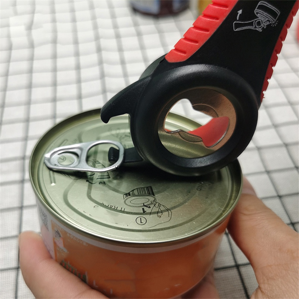 Ein Mehrzweck-Dosenöffner auf einer Dose, gehalten von einer Hand.