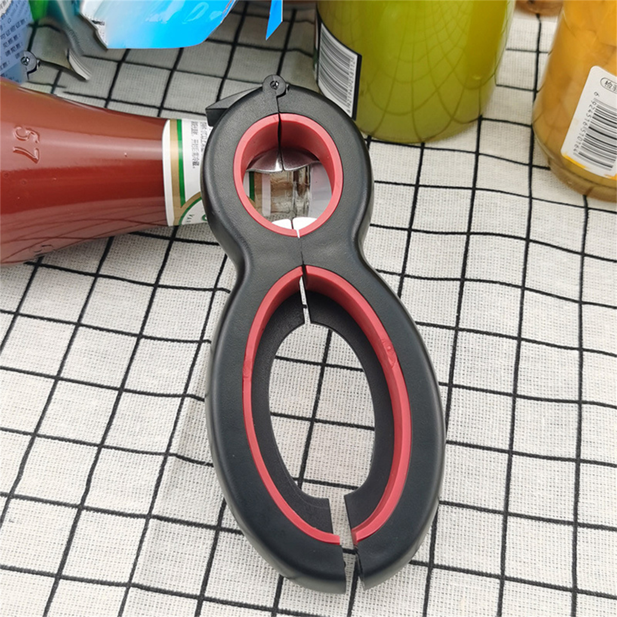 Schwarzer und roter Multi-Tool-Flaschenöffner. Es befindet sich auf einer karierten Oberfläche.