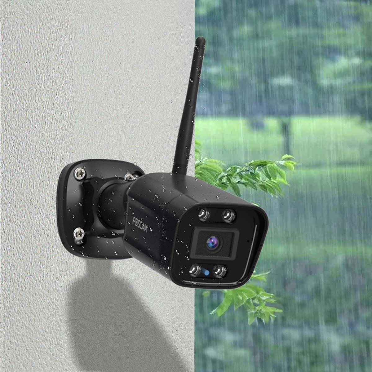 Eine schwarze Überwachungskamera an einer Wand montiert. Sie hat eine Antenne und blickt auf eine regnerische Szene.