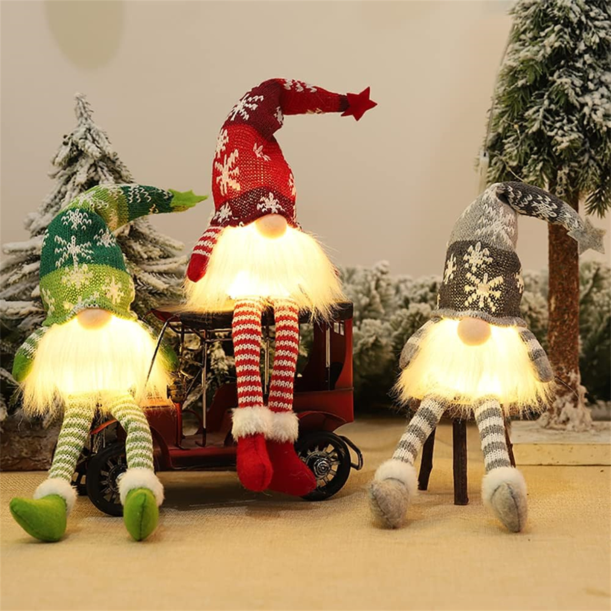 Drei Weihnachtswichtel mit leuchtenden Bärten. Schnee und Bäume im Hintergrund.