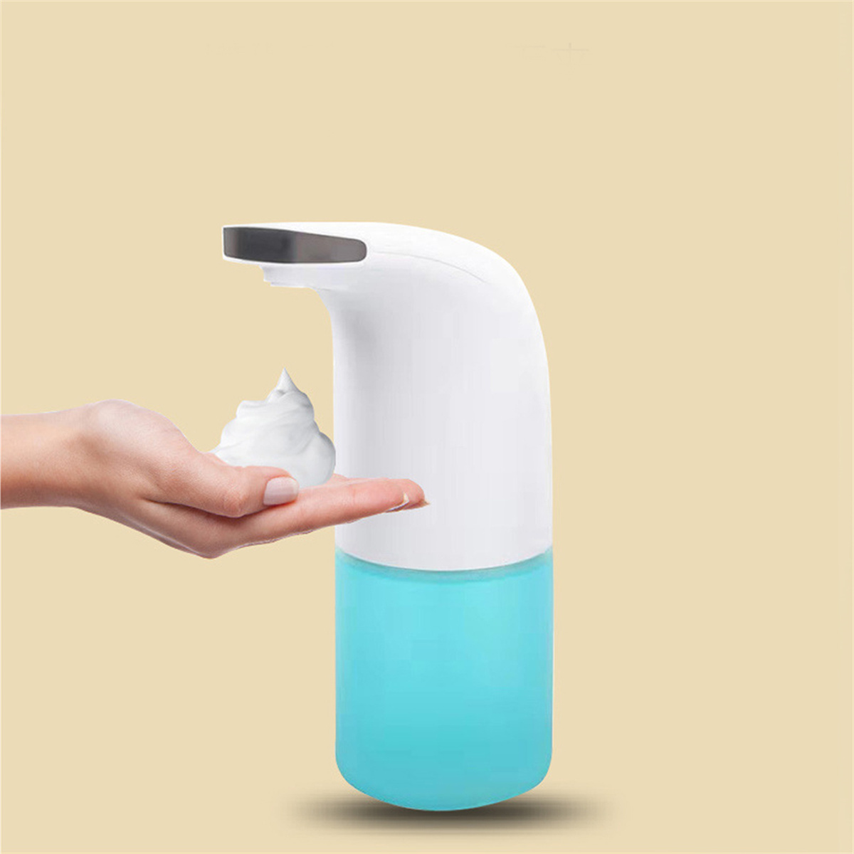 Ein weißer und blauer automatischer Seifenspender mit Schaum auf einer Hand, vor hellgelbem Hintergrund.