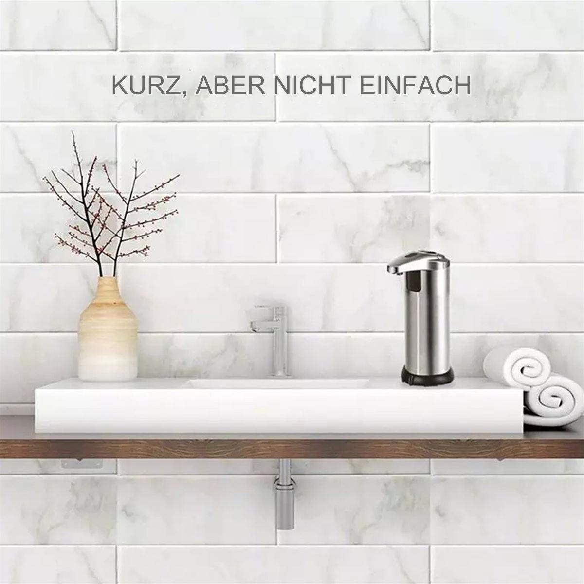 Moderner Seifenspender aus Edelstahl auf weißer Theke. Vase und Handtücher auf der Theke.
