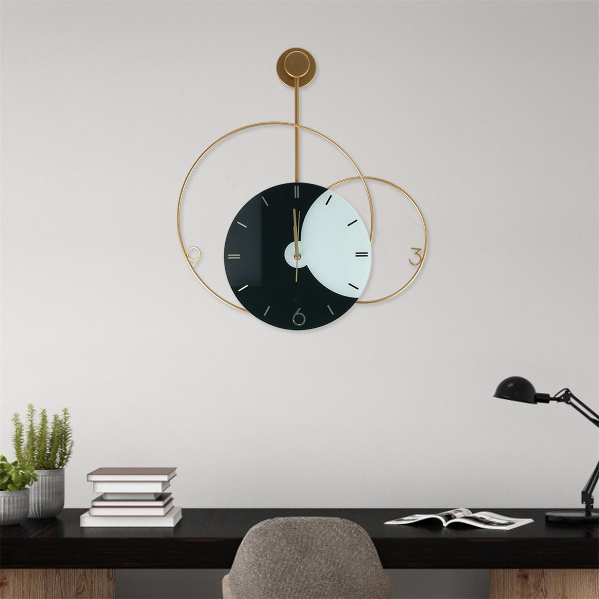 Eine goldene und schwarze Wanduhr mit rundem und halbkreisförmigem Design an weißer Wand.