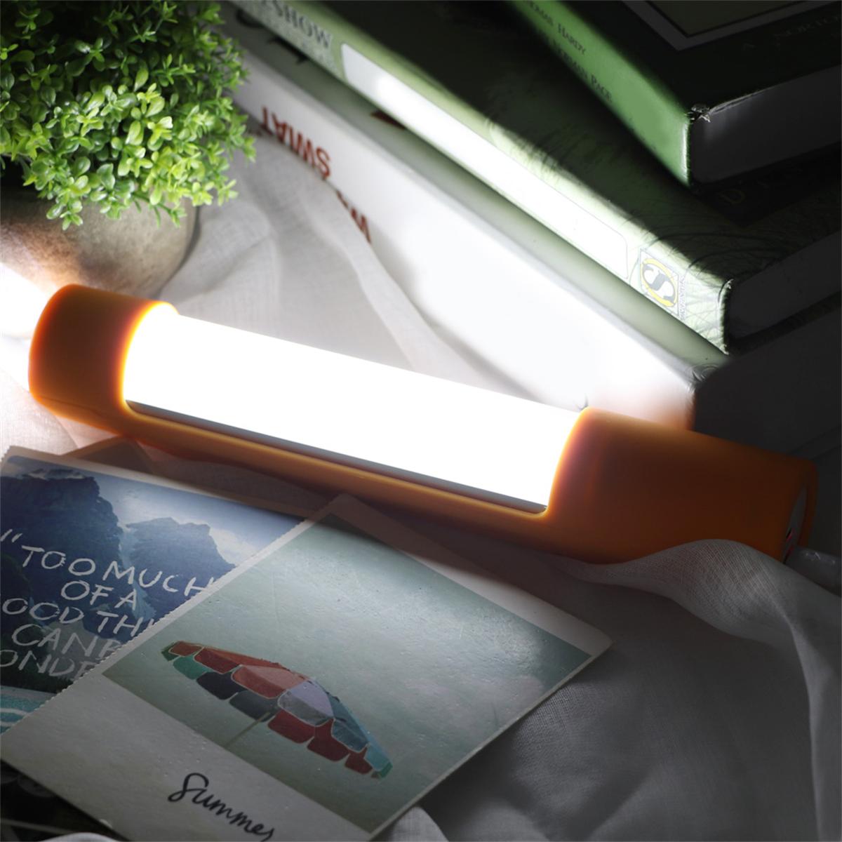 Eine orangefarbene LED-Lichtleiste auf einem Stapel Bücher, die ein warmes Leuchten wirft.