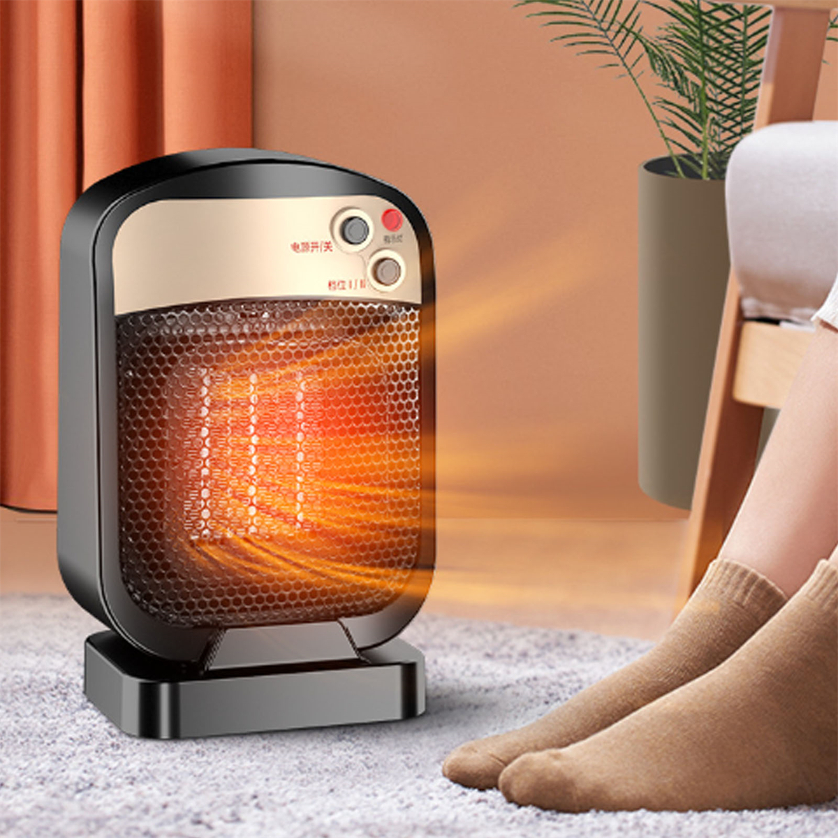Schwarz-goldener elektrischer Heizlüfter auf grauem Teppich. Beine und Füße einer Person sind sichtbar.