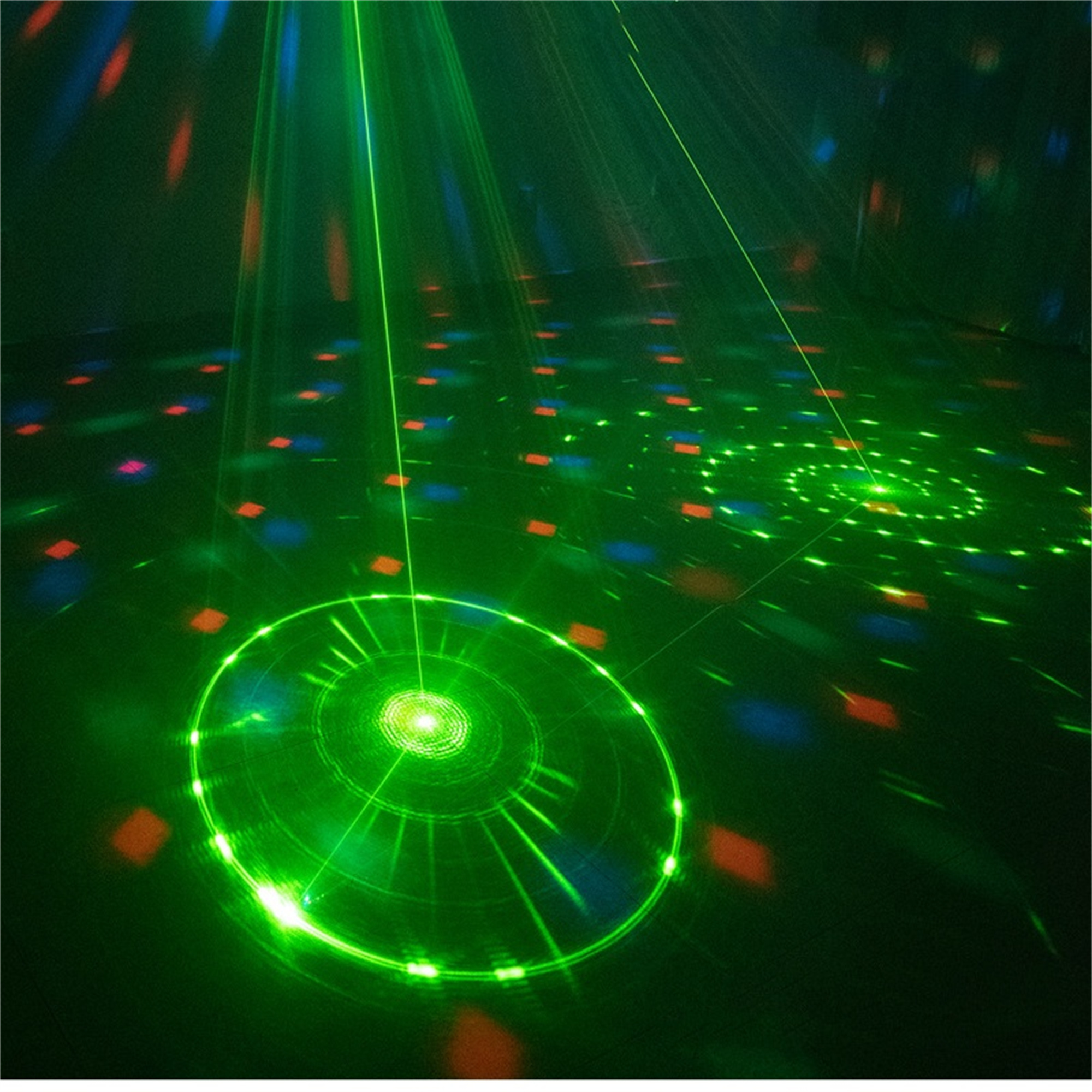 Grüne Laserstrahlen beleuchten einen dunklen Raum und erzeugen kreisförmige Muster auf dem Boden.