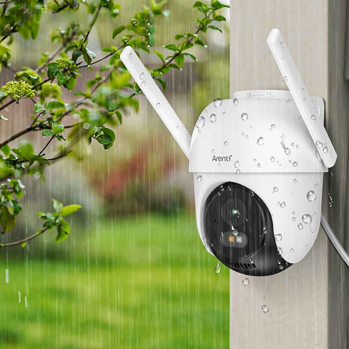 Eine weiße Überwachungskamera mit Antennen an einer Wand, mit fallendem Regen, deutet auf Außenüberwachung hin.