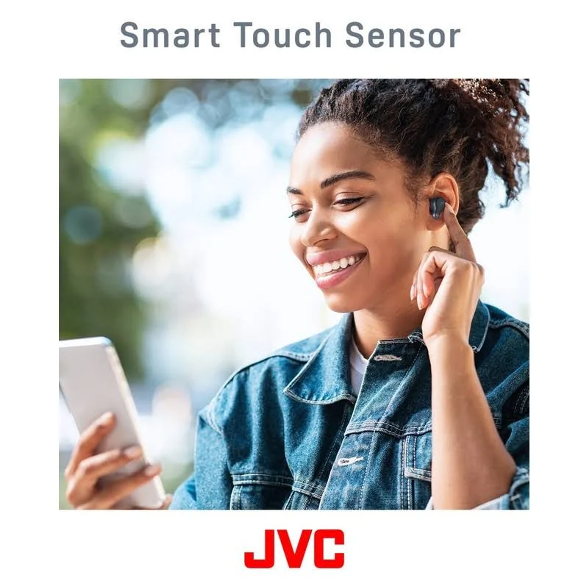 Donna che tiene in mano un telefono, indossa un auricolare JVC. Il testo sopra dice 'Smart Touch Sensor'.