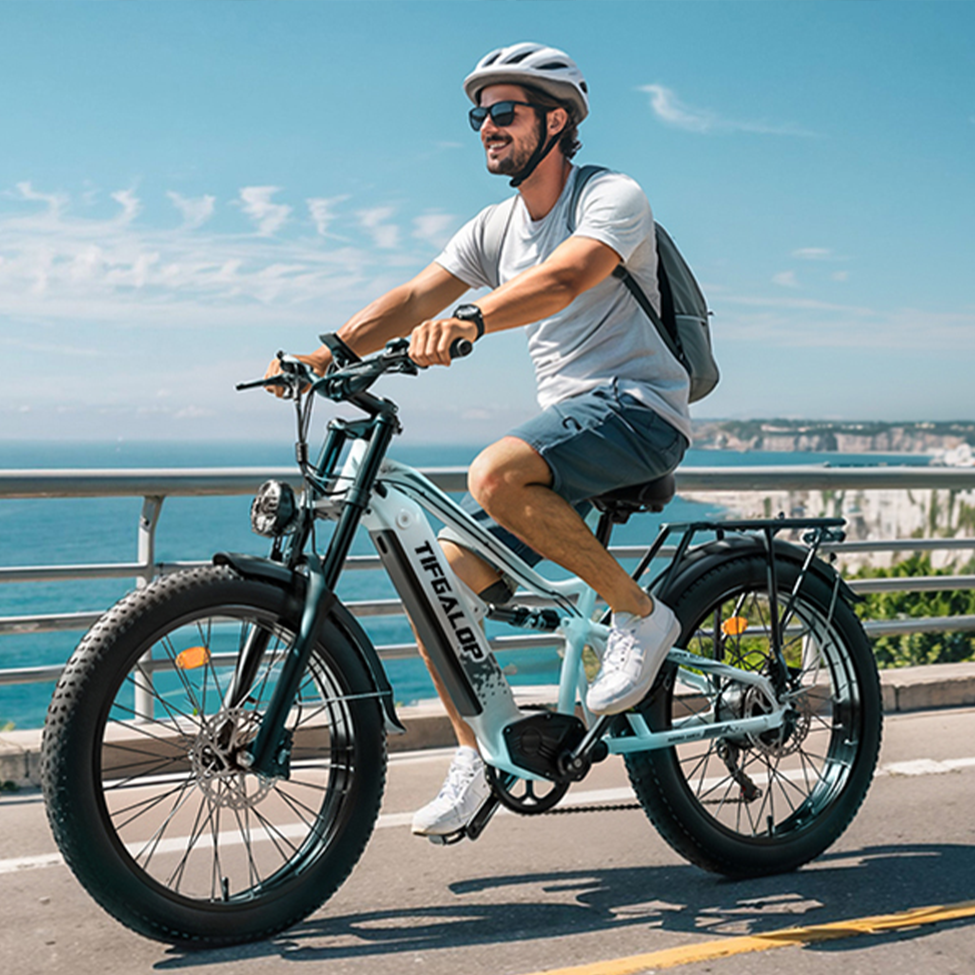 Mężczyzna jadący na jasnoniebieskim rowerze elektrycznym na drodze nad morzem.