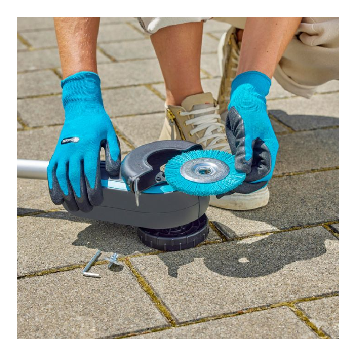 Person wearing blue gloves attaching a brush to a grey and blue gardening tool.