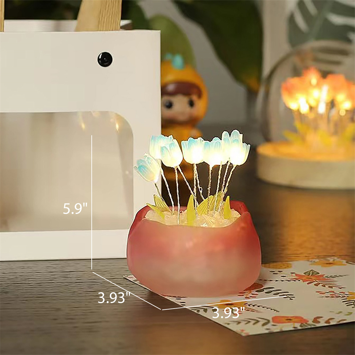 Ein dekorativer Blumentopf mit leuchtenden blauen Blumen und einer Geschenktüte im Hintergrund.
