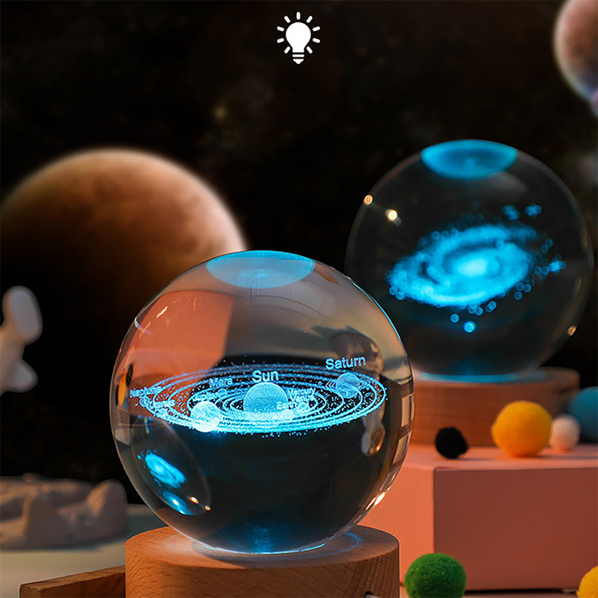 Glaskugeln mit beleuchteten Planeten und Galaxien. Holzsockel und bunte Kugeln sind ebenfalls sichtbar.