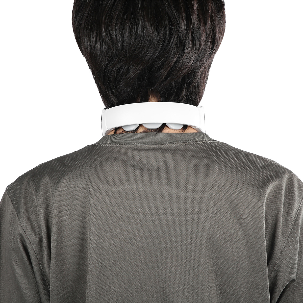 Eine Person von hinten mit einem Nackenmassagegerät. Das Massagegerät ist weiß.