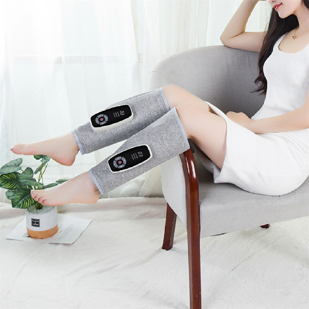 Eine Frau sitzt und trägt Beinmassager. Jeder Massager hat ein Bedienfeld.