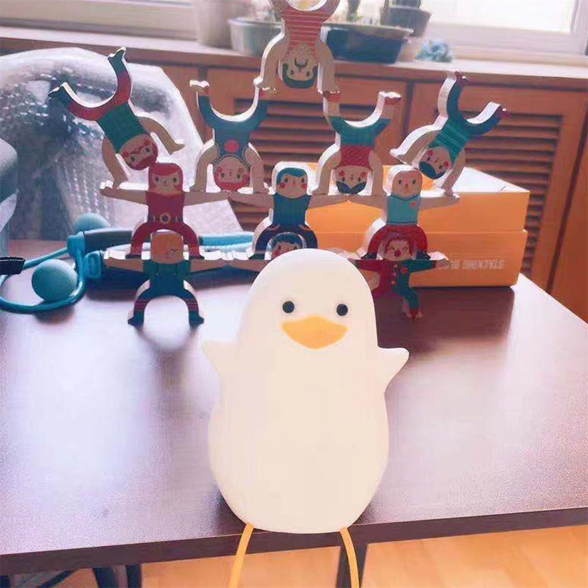 Weißes Enten-Nachtlicht mit Armen. Holzspielzeug im Hintergrund auf einem Regal.
