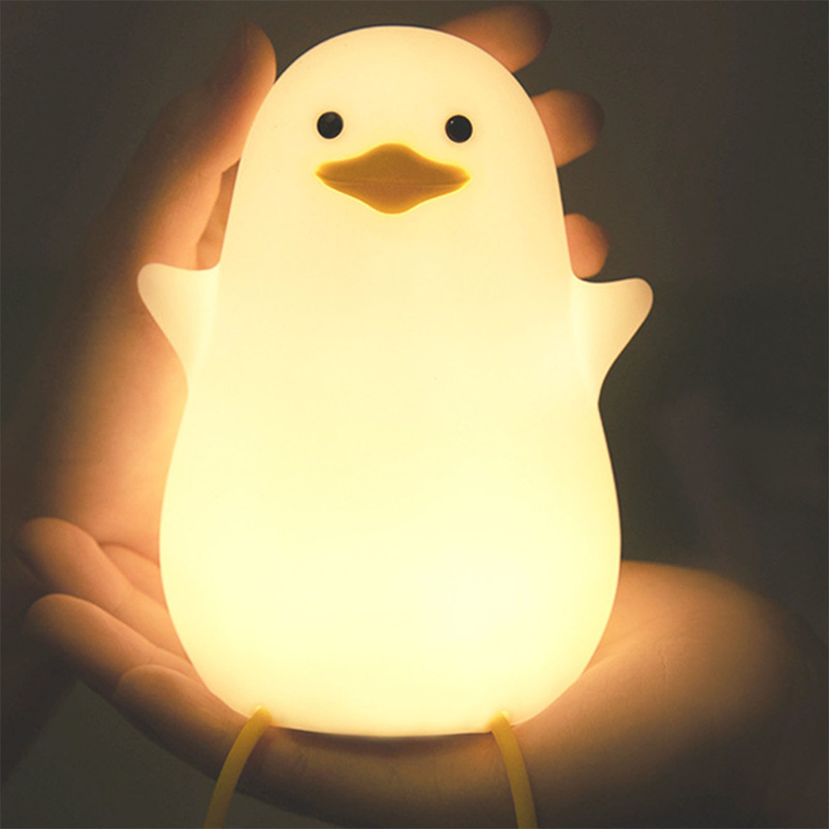Ein leuchtendes weißes Enten-Nachtlicht wird von einer Person gehalten. Das Licht beleuchtet die Hände der Person.