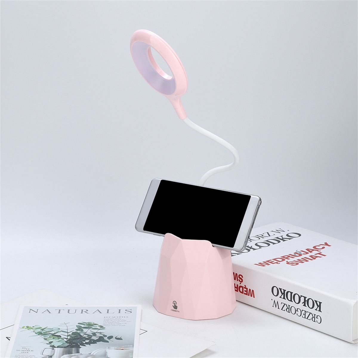 Rosa Schreibtischlampe mit Telefon. Weißer Hintergrund mit Büchern.