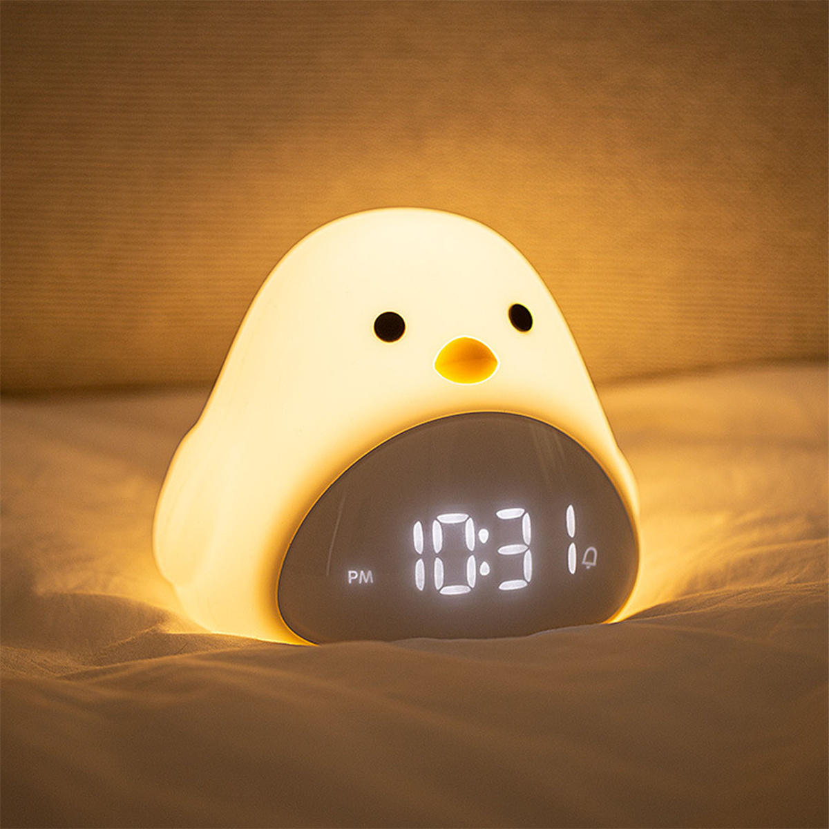Ein niedlicher, weißer Küken-Wecker, der 22:31 Uhr auf einem Bett anzeigt.