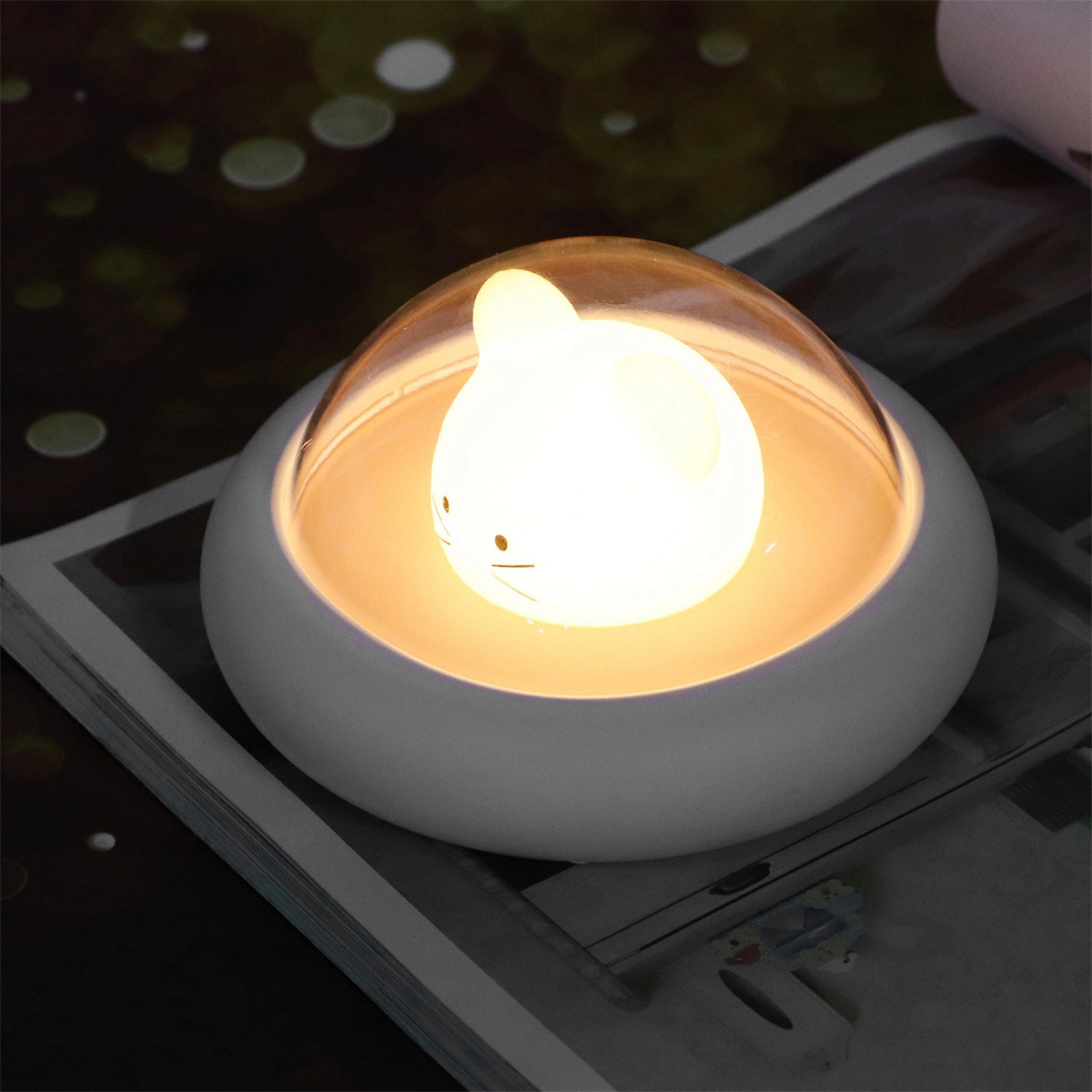 Eine weiße Lampe in Form einer Maus mit leuchtendem Licht im Inneren.