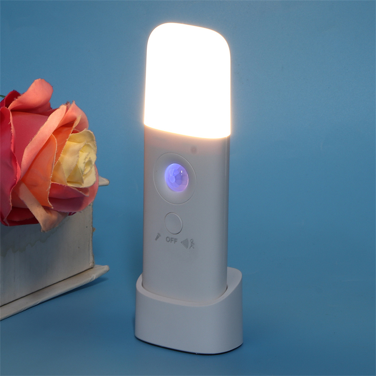 Weißes Nachtlicht mit Sockel und Lichtsensor, beleuchtet.