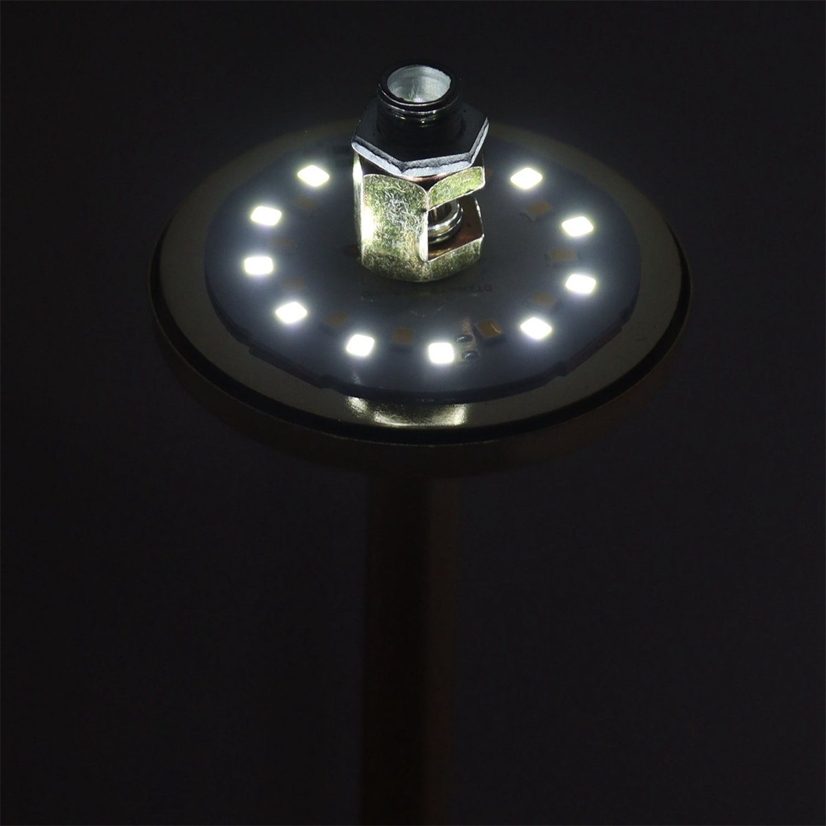 Eine beleuchtete LED-Leuchte vor schwarzem Hintergrund. Die Lichtquelle befindet sich in der Mitte der Leuchte.