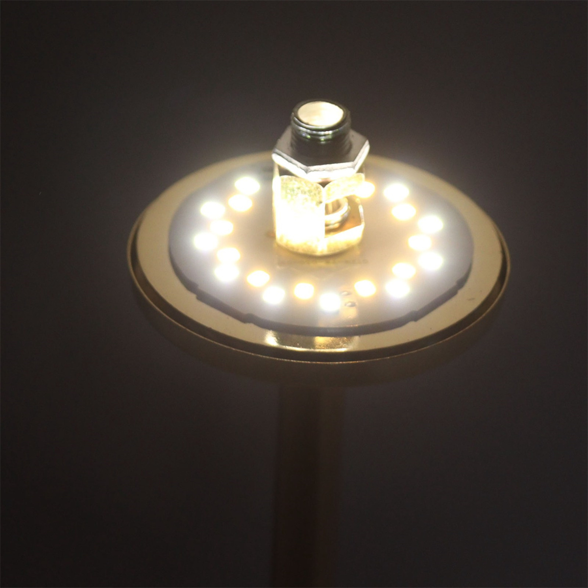 Eine goldene Lampe mit einem Lichtring auf schwarzem Hintergrund.