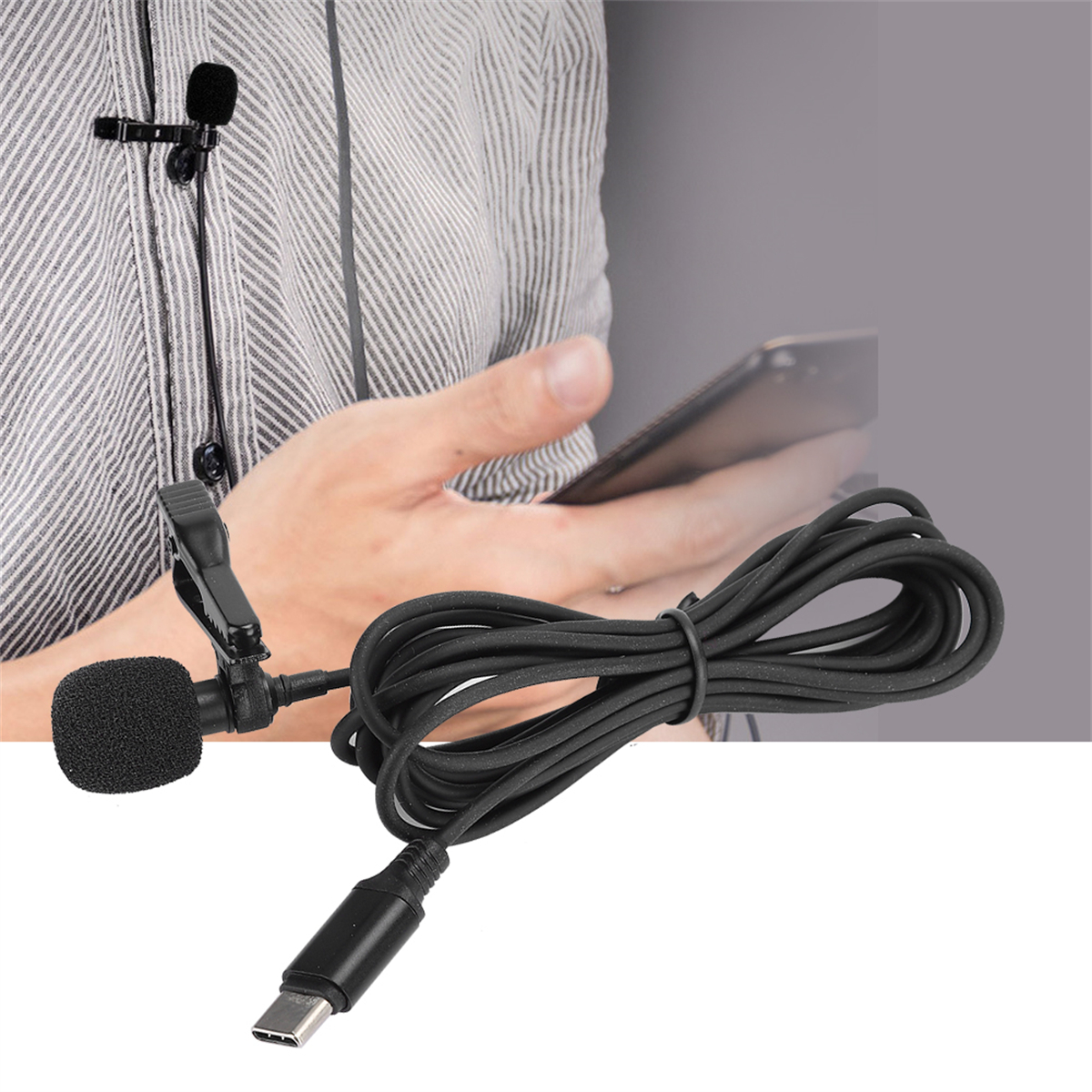 Ein schwarzes Mikrofon und Kabel, die an einem Hemd befestigt sind. Ein Telefon und ein verschwommener Hintergrund sind sichtbar.