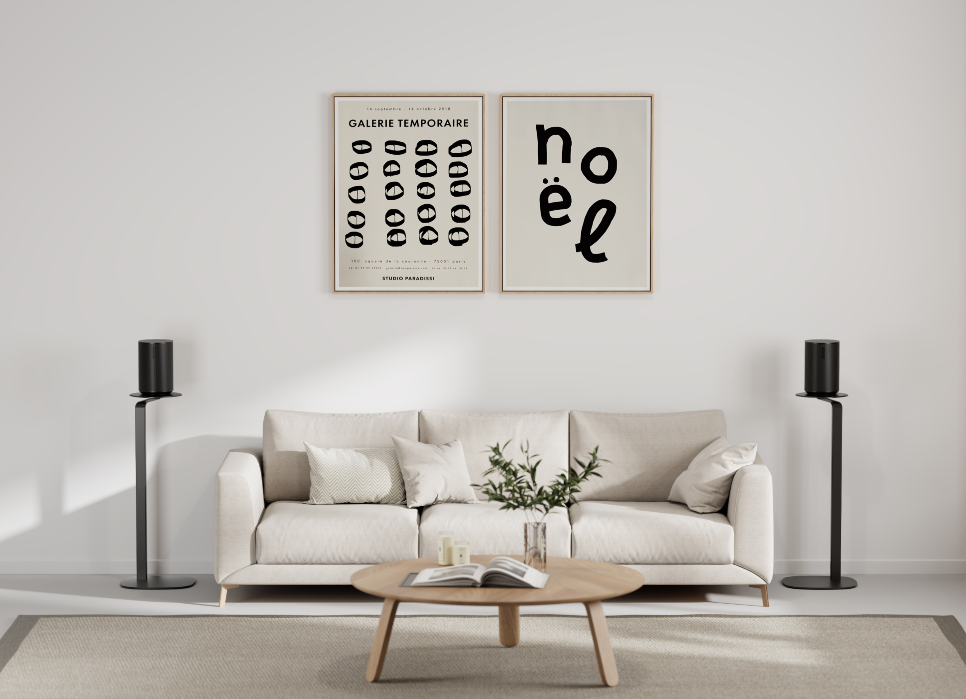 Ein Wohnzimmer mit beigem Sofa, zwei Lautsprechern und zwei gerahmten Kunstwerken. Ein Couchtisch und ein Teppich sind vorhanden.