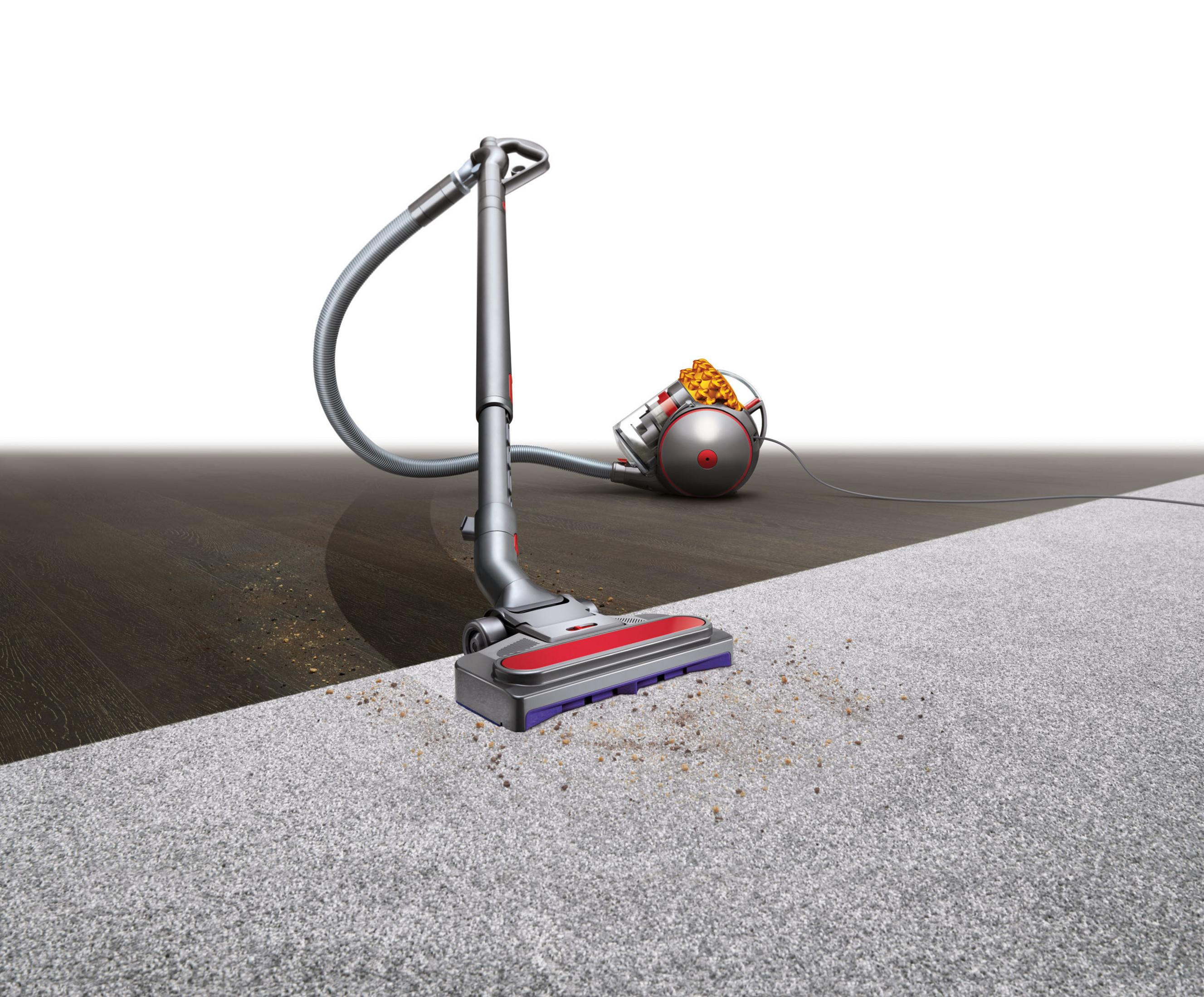 Dyson-Staubsauger auf Teppich und Holzboden. Schmutz ist auf Teppich und Holz sichtbar.