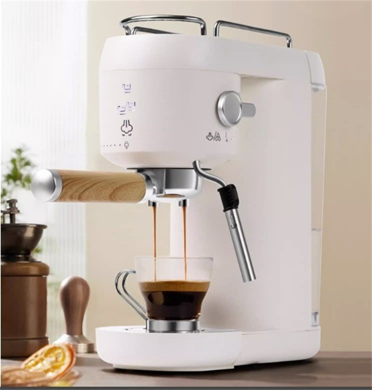 Eine weiße Espressomaschine brüht Kaffee in eine Glastasse. Ein Mahlwerk und ein Tamper befinden sich in der Nähe.
