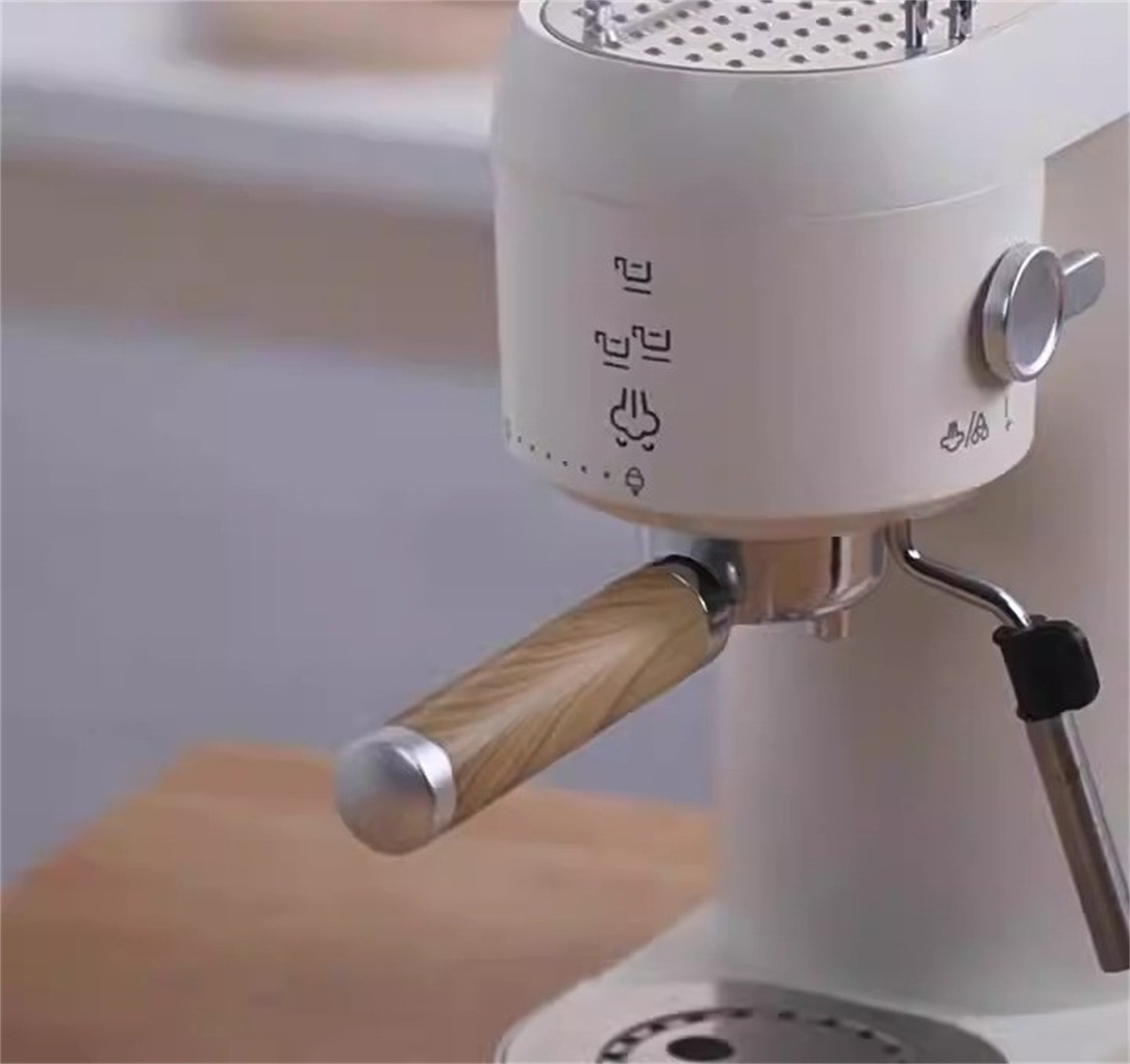 Nahaufnahme einer weißen Espressomaschine mit Holzgriff. Sie hat verschiedene Symbole und eine silberne Düse.