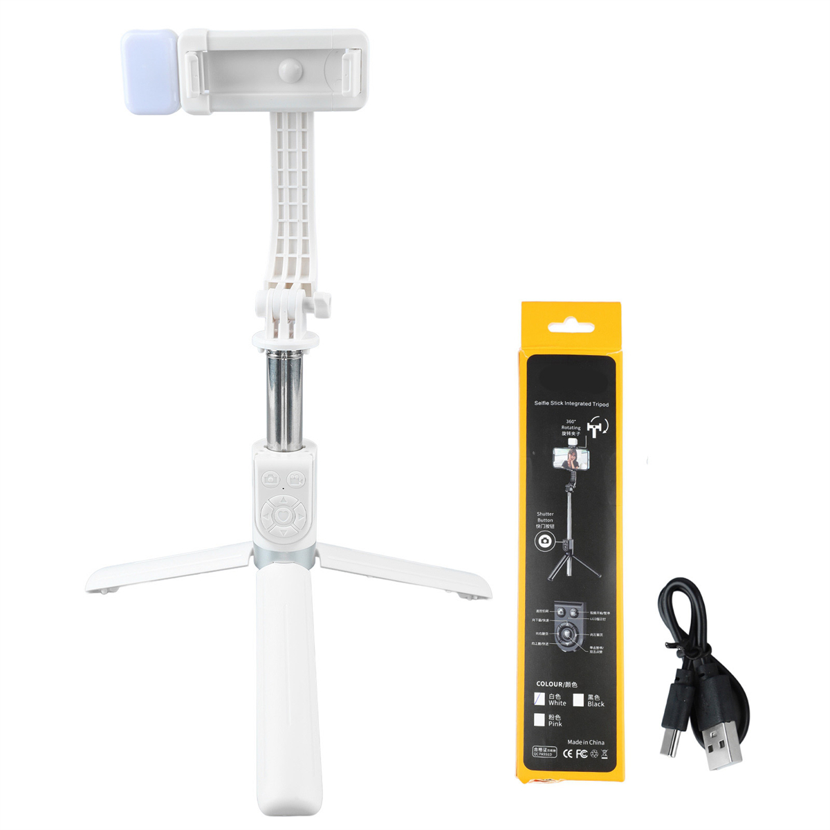 Weißes Selfie-Stick-Stativ mit Telefonhalter und eine kleine Box mit USB-Kabel daneben.