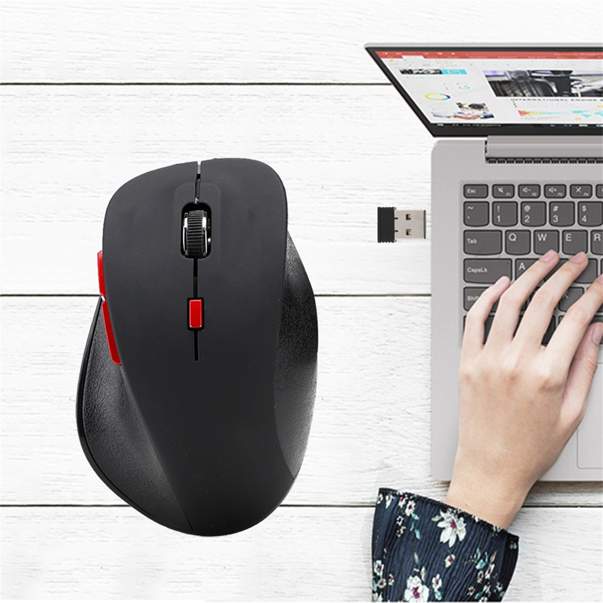 Schwarze ergonomische Computermaus mit roten Tasten neben einem Laptop.