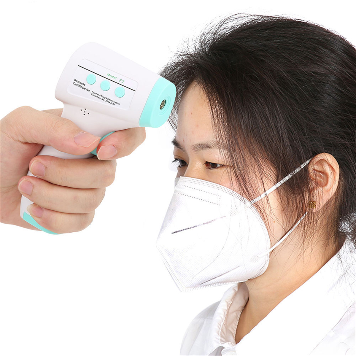 Person misst Temperatur mit Thermometer. Person trägt Maske. Weißer Hintergrund.