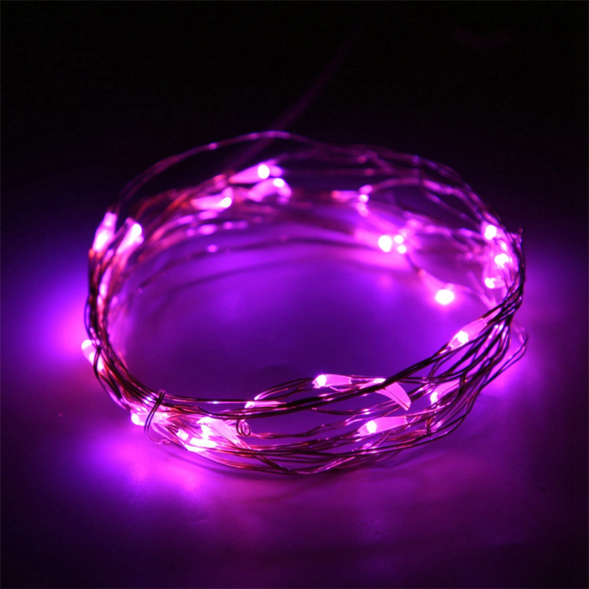 Gewickelte Lichterkette, die auf dunkler Oberfläche ein violettes Leuchten aussendet.