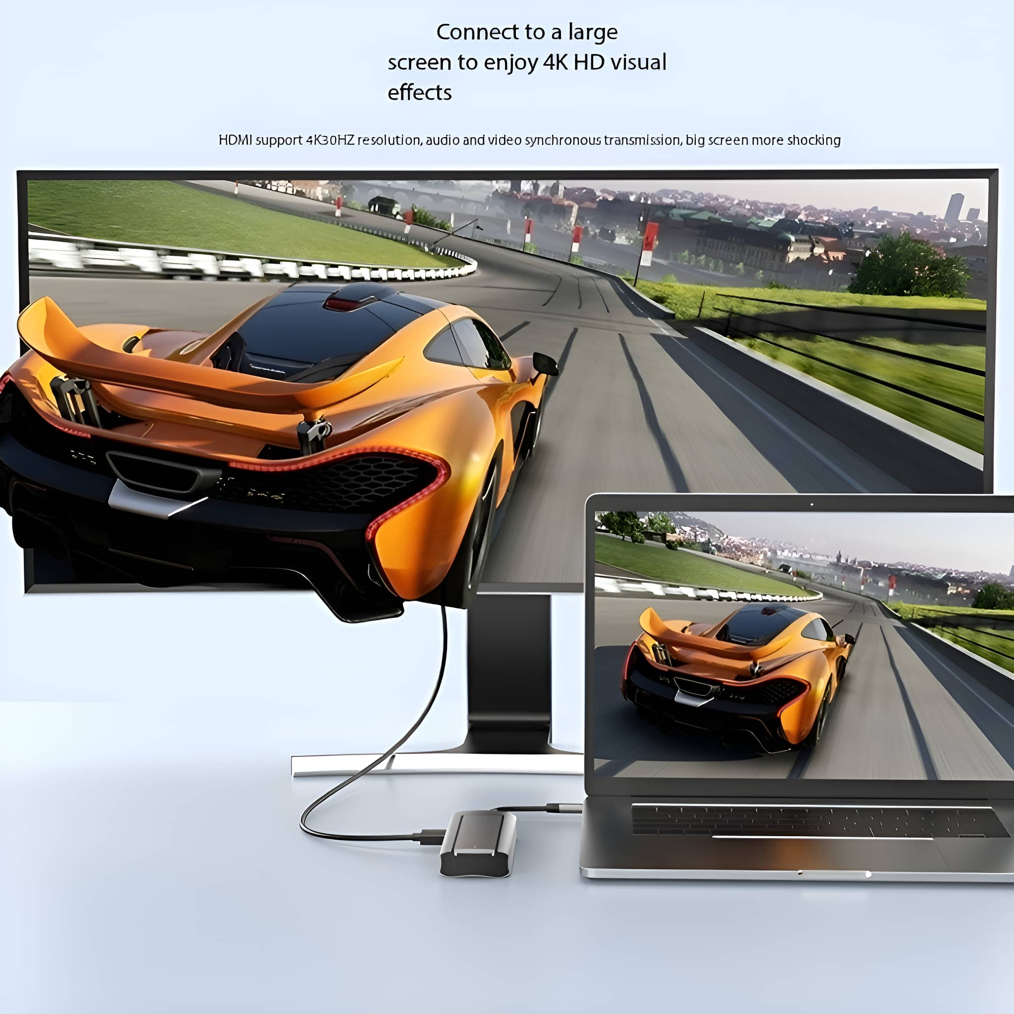 Ein Computer-Setup mit einem Autorennen auf dem Bildschirm, das mit einem Laptop und einem großen Monitor verbunden ist.