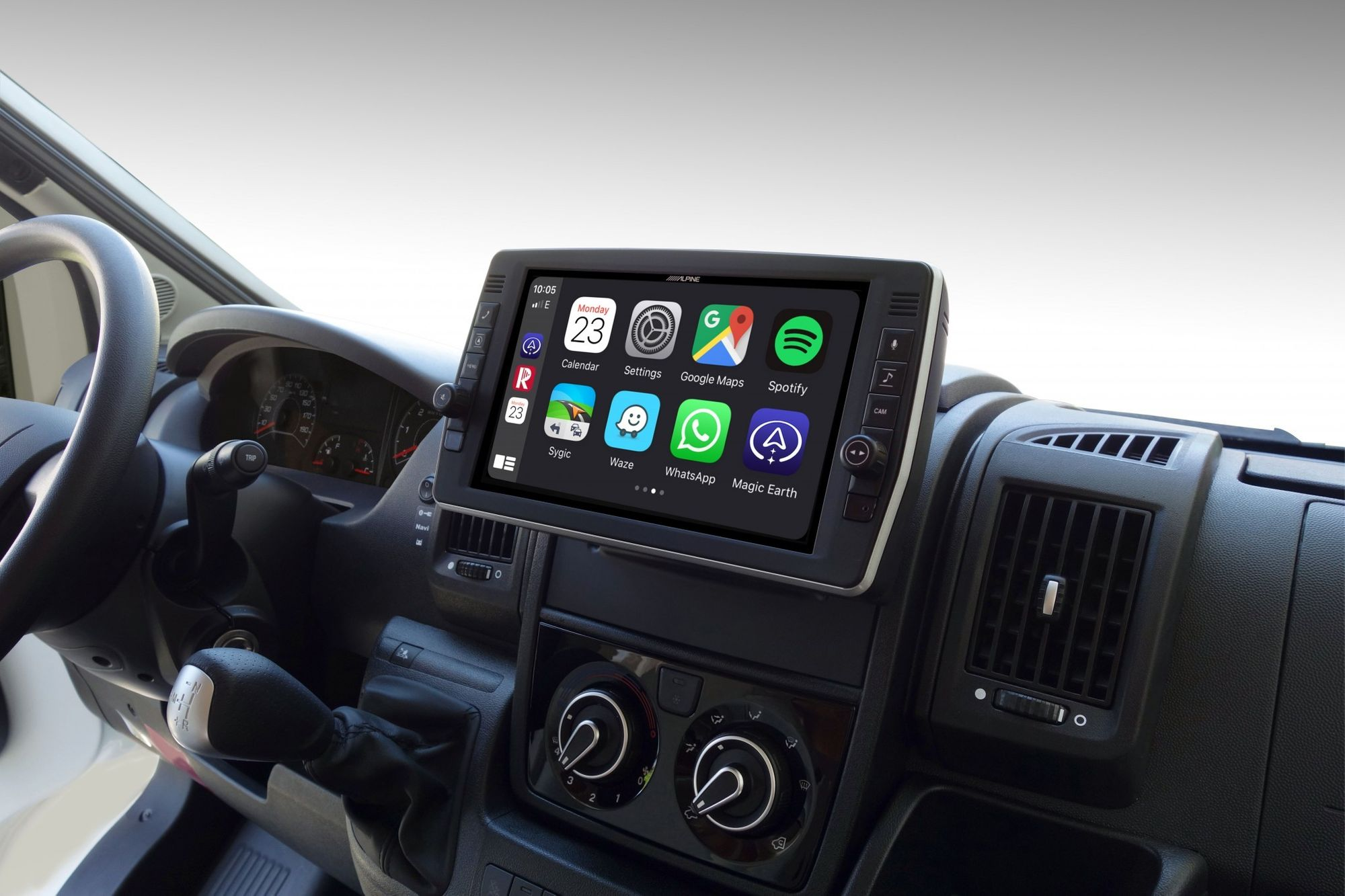 Armaturenbrett eines Autos mit einem Bildschirm, der eine Karte und App-Symbole zeigt. Lenkrad sichtbar.