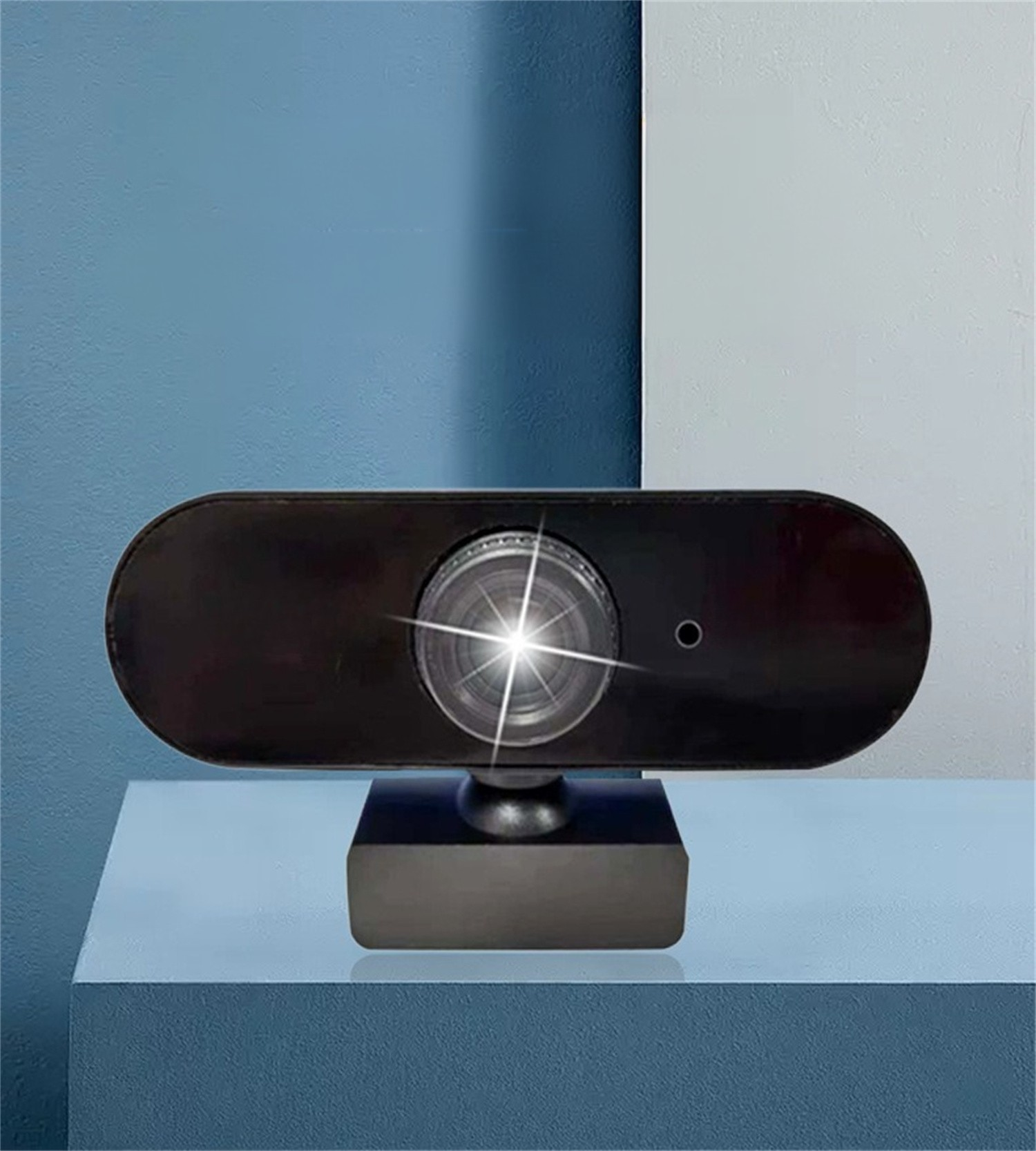 Eine schwarze Webcam auf einem Ständer, mit Linse und Licht, vor blau-weißem Hintergrund.