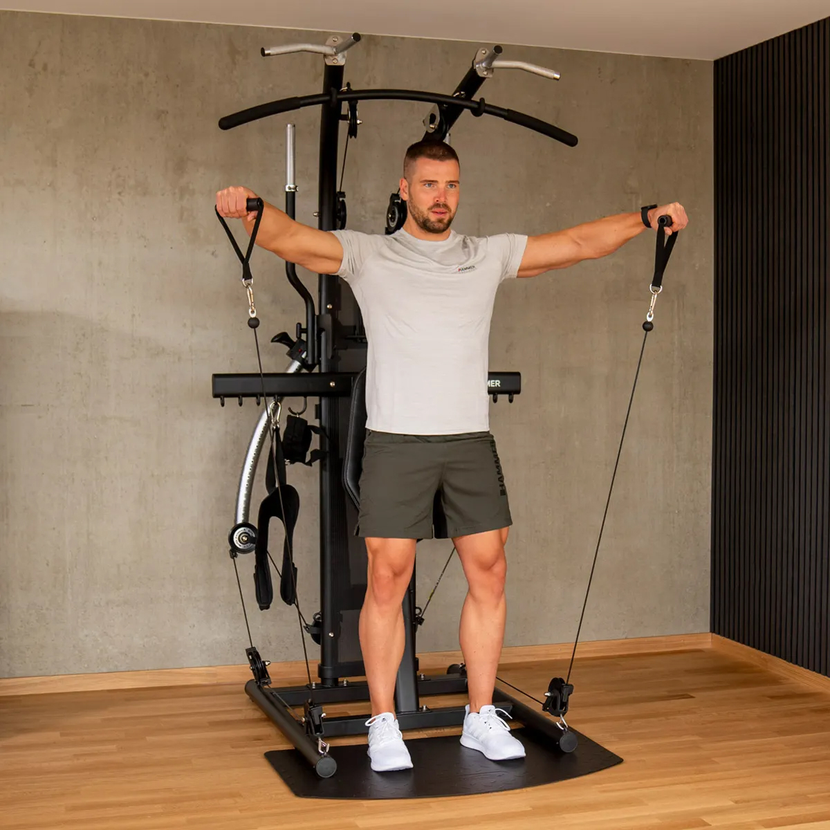 Mann trainiert an einem Heimtrainingsgerät. Er hält Griffe.