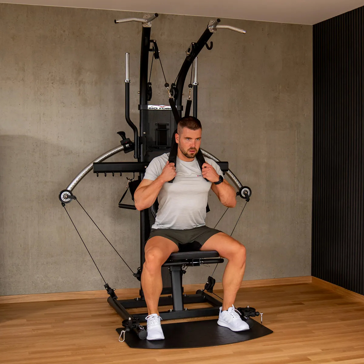 Ein Mann sitzt auf einem Fitnessgerät und hält die Griffe, bereit zum Trainieren.