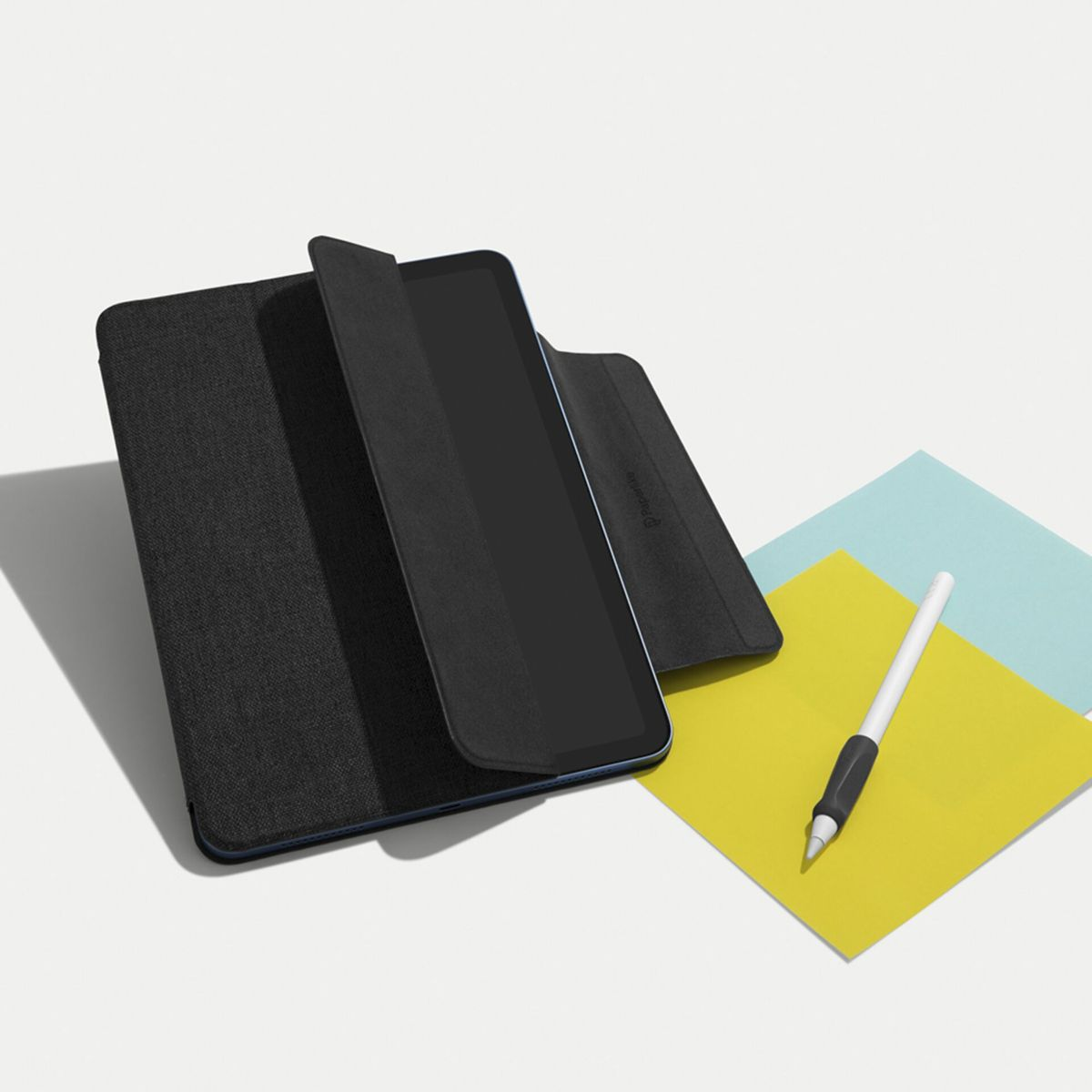 Eine schwarze Tablet-Hülle mit dunkelblauem Innenraum, mit einem Stift und gelben und blauen Haftnotizen.