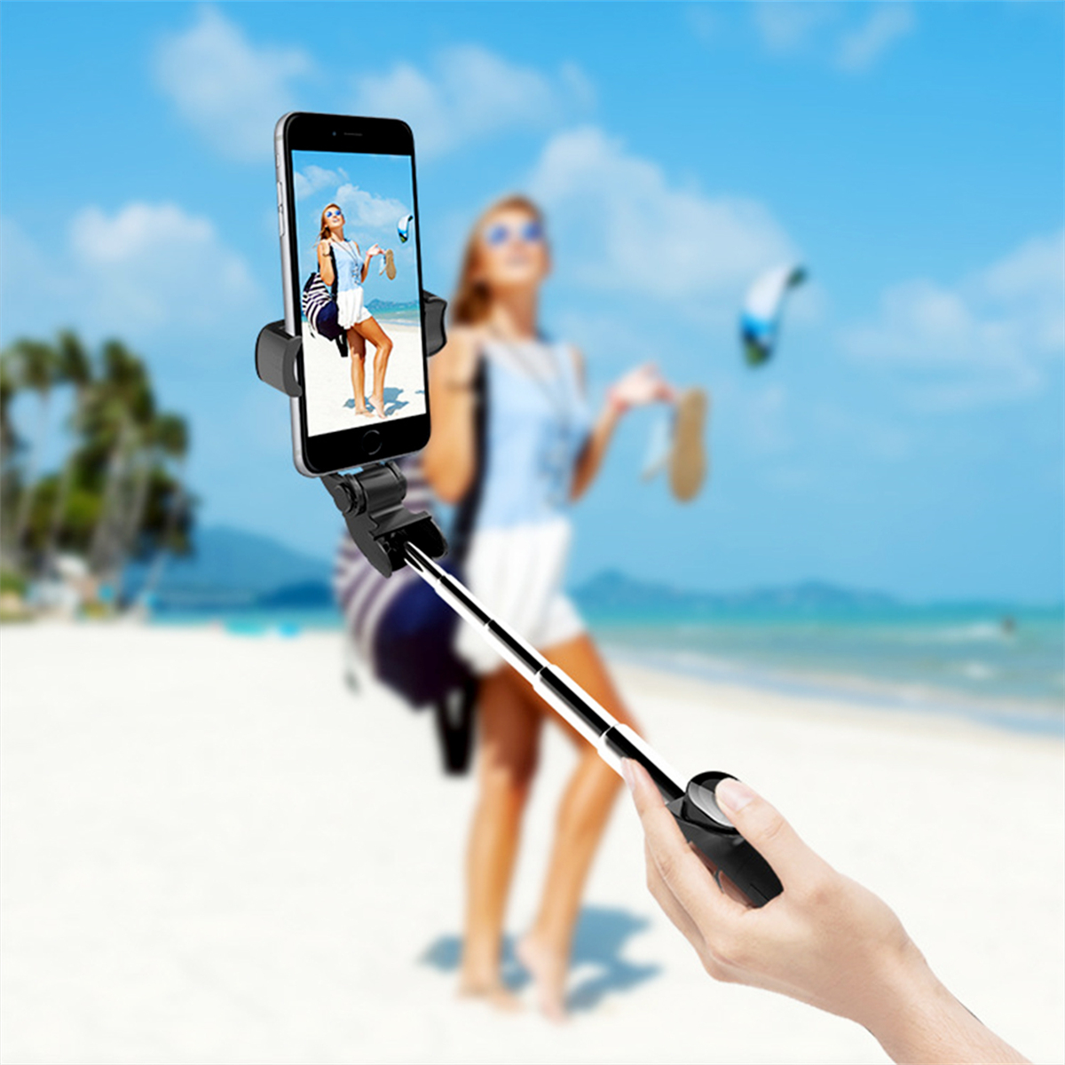 Person hält Telefon mit Strandfoto, eine Person hält Selfie-Stick.