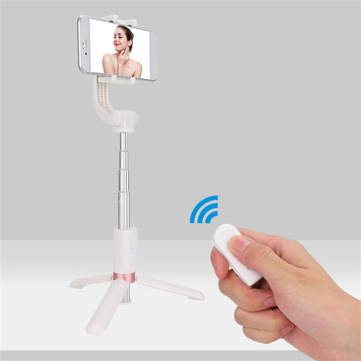 Ein weißer Selfie-Stick mit einem Telefon, das das Gesicht einer Frau zeigt. Eine Fernbedienung ist in einer Hand.