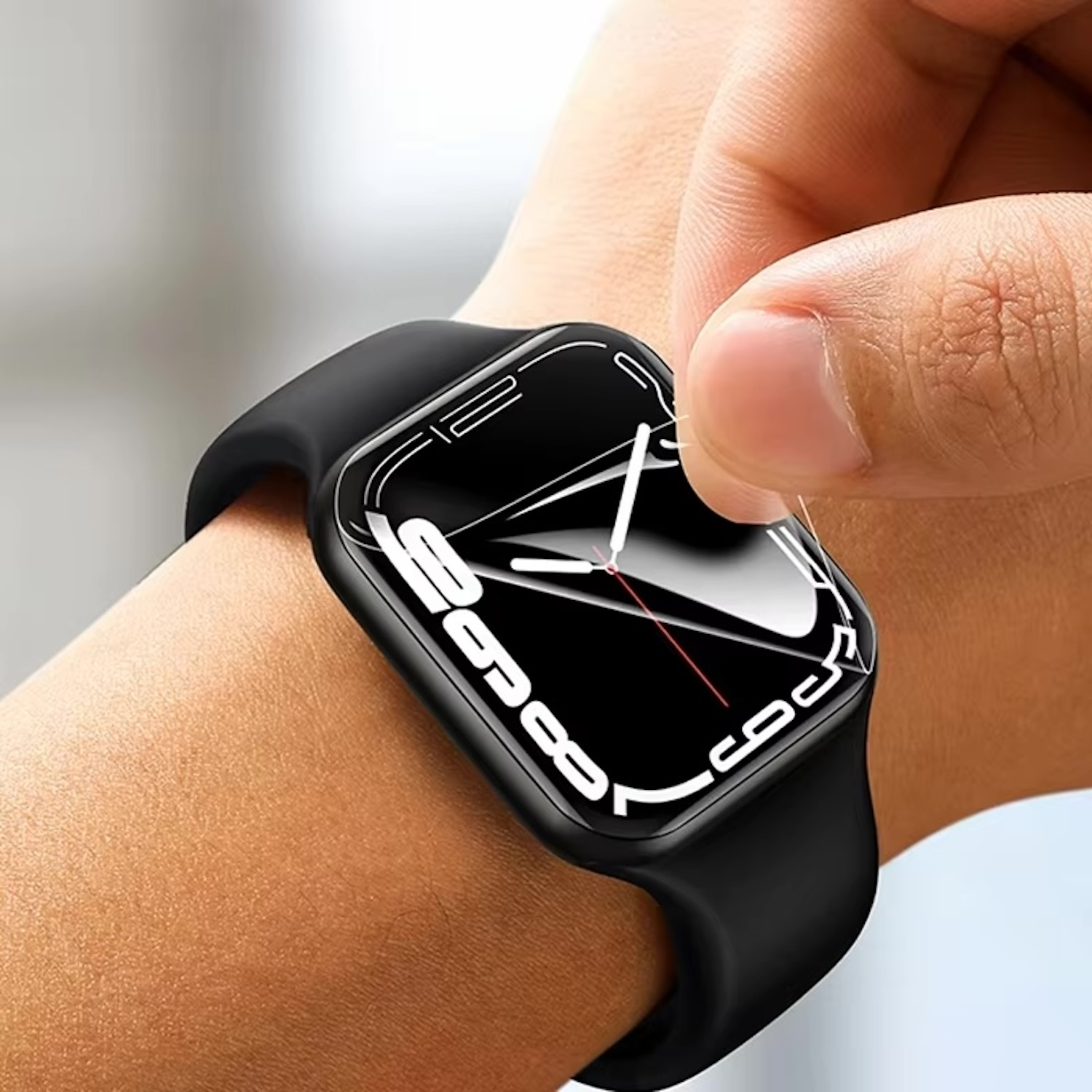 Die Hand einer Person, die eine Displayschutzfolie von einer schwarzen Smartwatch mit schwarzem Armband abzieht.
