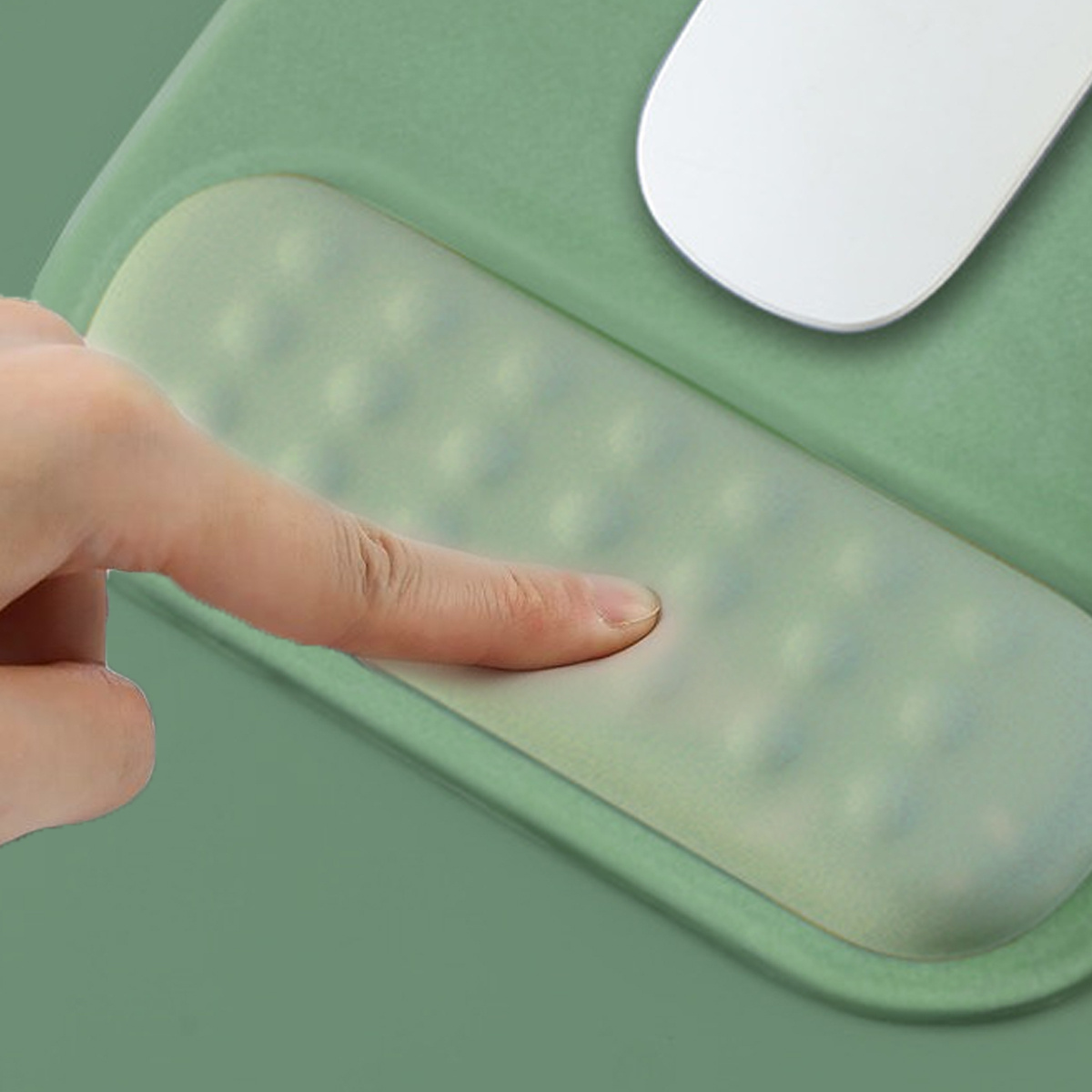 Eine Hand drückt auf ein weiches, grünes Mauspads mit einer Handgelenkauflage.