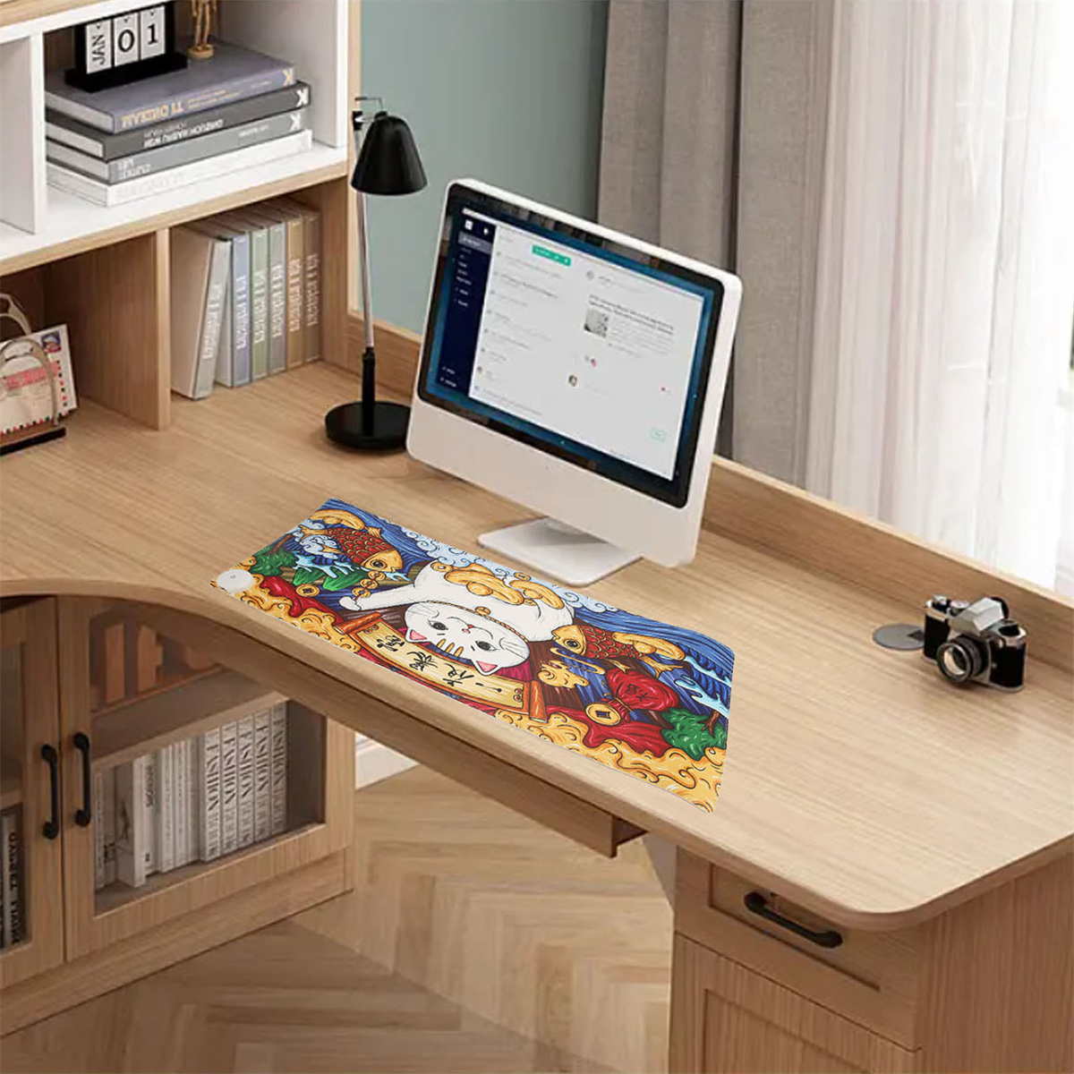 Schreibtisch mit Monitor, Tastatur, Lampe und einer dekorativen Matte. Bücherregal im Hintergrund.