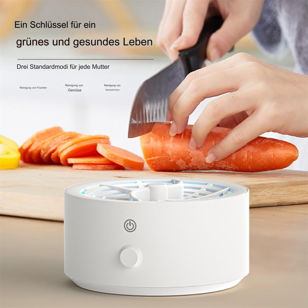 Eine Person schneidet eine Karotte über einem weißen Gerät mit einem Knopf. Geschnittene Karotten sind im Vordergrund.