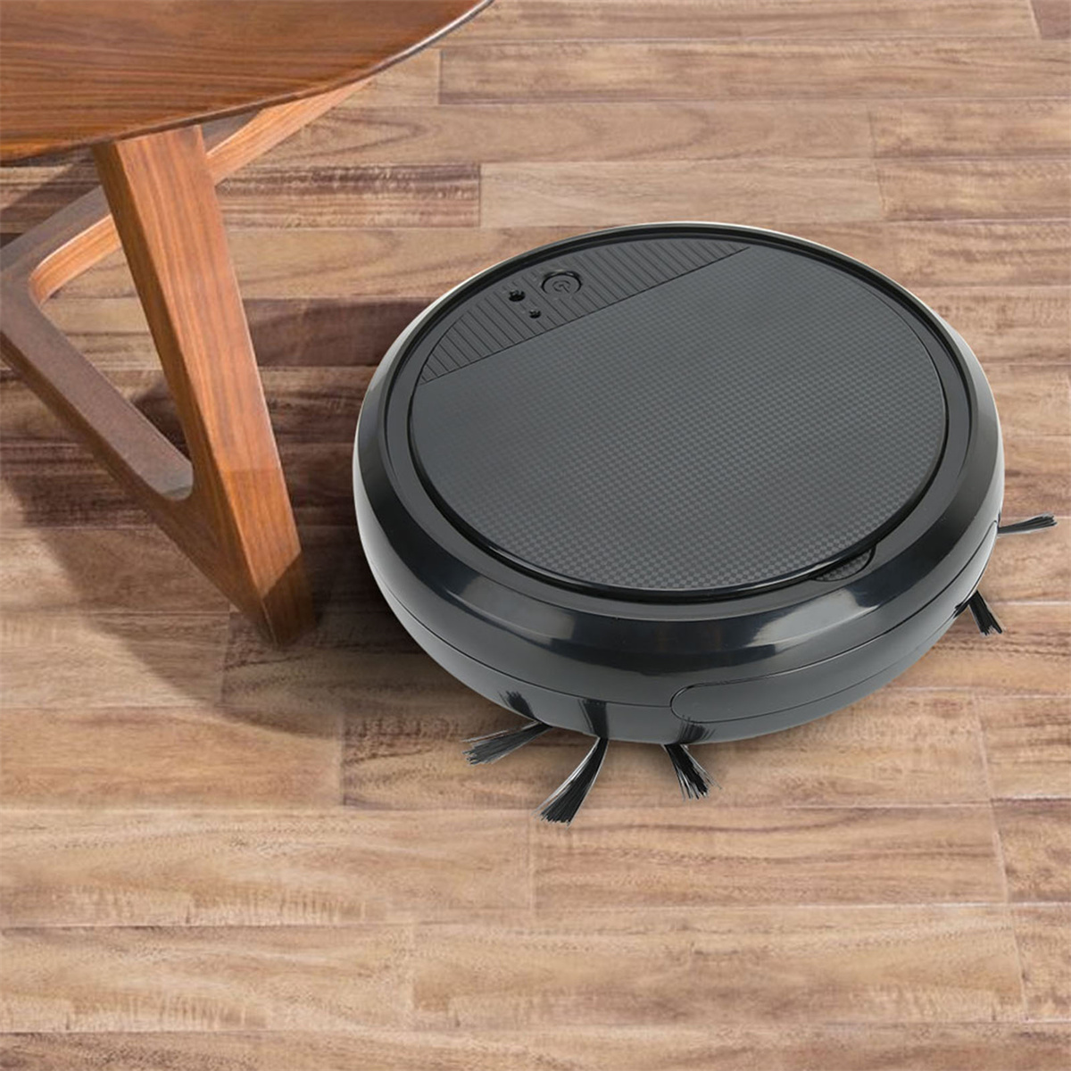 Ein schwarzer Roboter-Staubsauger auf einem Holzboden, in der Nähe eines Holztisches.
