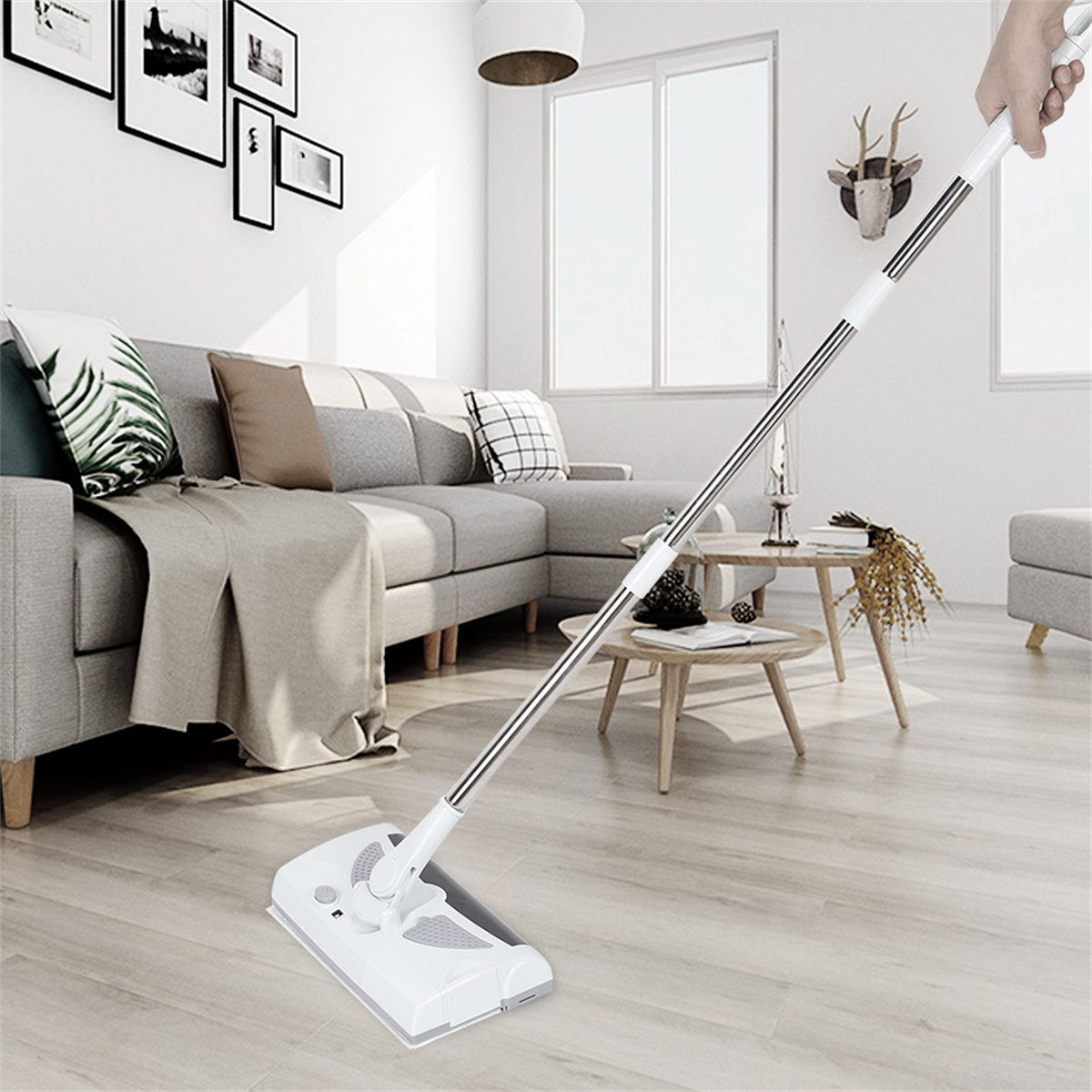 Ein weißer elektrischer Bodenwischer wird in einem Wohnzimmer mit grauem Sofa, Holztischen und einem Teppich verwendet.