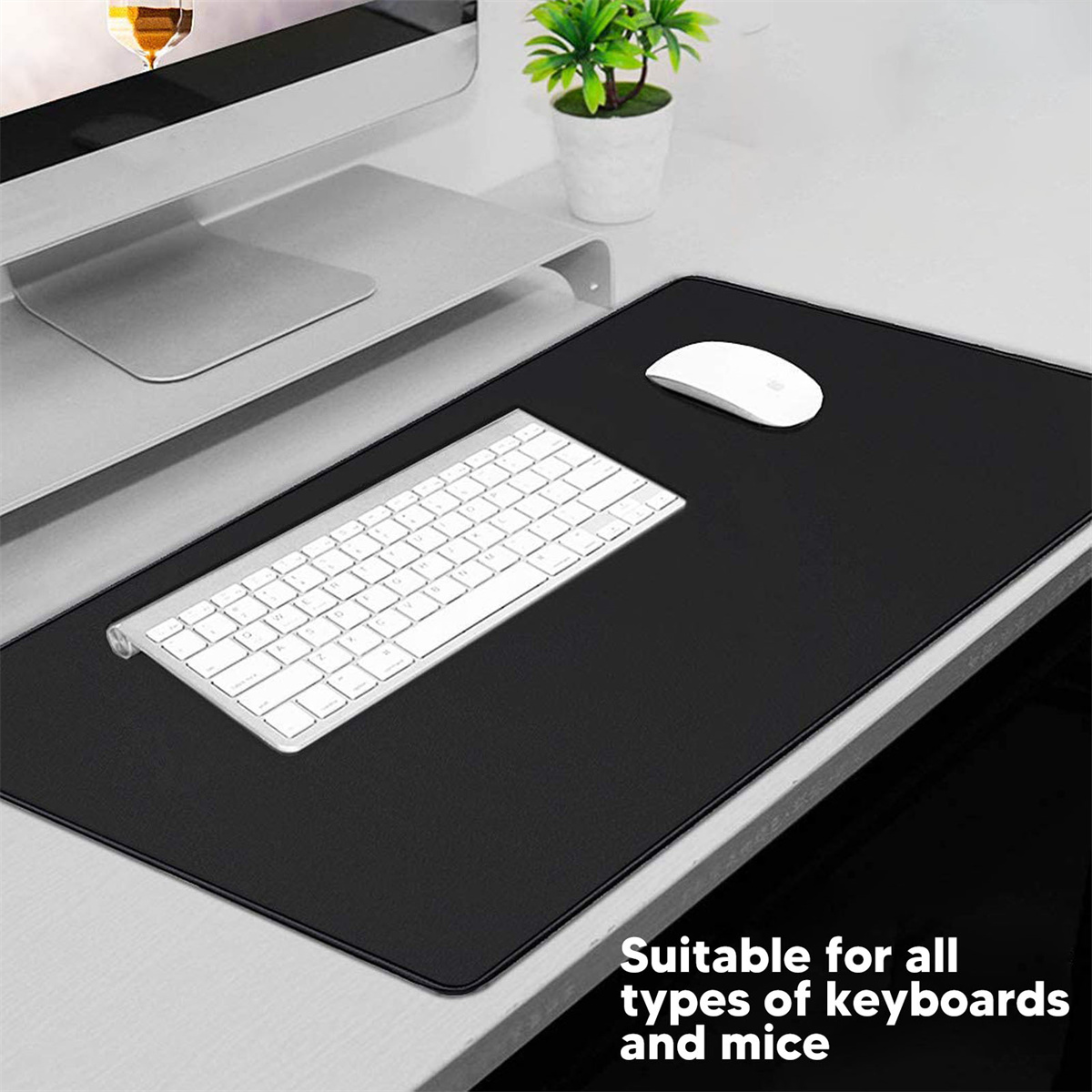 Ein schwarzes Mousepad, eine weiße Tastatur und eine weiße Maus auf einem grauen Schreibtisch.